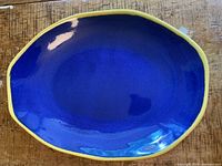 Top view of the oval platter showing deep royal blue glossy interior with lemon yellow edge.