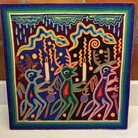 Front view of wool on board knitted artwork with three stylized antlered figures holding candles and orbs in multicolored yarn.