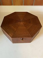 Top view of the closed hexagonal teak wood box showing the mitred teak pattern lid and the round wooden knob.
