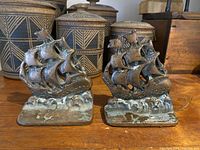 Pair of copper sailboat bookends showing both from the front with patina and base wear visible.