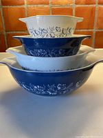 Stacked view of the four Pyrex Cinderella bowls alternating blue and white with Colonial Mist floral pattern