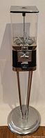 Full view of the entire gumball machine, showing clear container, chrome pedestal base, and overall design.