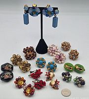 Full lot of vintage earrings displayed against a white background showing various colors and styles, including dangling and cluster bead designs.