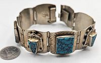 Close-up of the link bracelet showing the textured metal and faux turquoise stones with a quarter for scale.