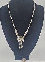 Front view of vintage Jay Flex sterling rhinestone necklace displayed on black bust with a quarter for size reference.