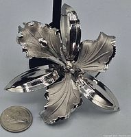 Close-up of the large sterling silver flower brooch with matte and polished petals next to a quarter for size reference.