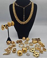 Full view of jewelry laid out including leaf necklace, earrings on stand and assorted brooches and earrings on surface