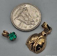 Small green stone pendant and gold charm sized next to Canadian dime for scale.