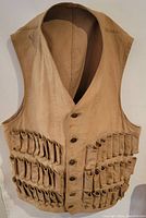 Front view of vintage tan shotgun shell vest with sewn pockets for shotgun shells and button front.