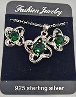 Full set displayed on card marked '925 Sterling Silver', includes pendant necklace and matching stud earrings with green stones.