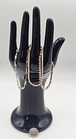 Three sterling silver bracelets displayed on a black hand stand for size reference.