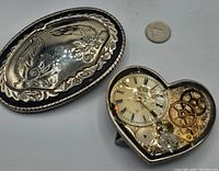 Two belt buckles shown side by side showing detail and relative size to a quarter coin