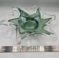 Angled view of the green and clear Murano glass dish with a stainless steel ruler showing about 10 inches size.