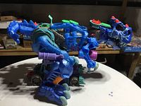 Side view of the large blue dinosaur toy showing detailed plastic molding, articulated claws, wheels on feet and interactive buttons.