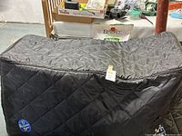 Full side view of the large black quilted cooler bag with a tag attached showing its size and material.