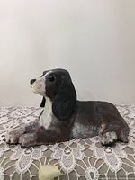Side view of hollow ceramic Beagle dog figurine lying down on a lace tablecloth.