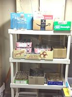 Boxes and trays containing various canning jars of different sizes and types arranged on shelving unit in basement area.