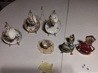 Overview of miniature cups, saucers, trinket boxes, and lace doily representing the lot contents with varied Chinese and collectible items.