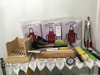 Full lot display showing all items on table including aprons, bread slicer, cutting board, ladles, thermometer, and tongs