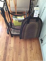 Side angle of wrought iron fireplace tool holder with tools, log carrier, and large box of Duraflame fatwood fire starter on hardwood floor.