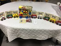 Wide shot of nine original packaged Montgomery Schoolhouse Scoots laid out plus the boxed workbench tool truck, all vintage wooden toys.