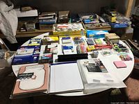 Wide view of all assorted office supplies spread out on table including pads, pens, kits, and tools.