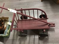 Top view of vintage red wooden wagon showing interior and side slats with handle lying across the wagon.
