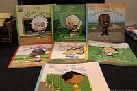 Ten Scholastic children's books from the "I Am" series laid out with visible colorful cartoon-style illustrated covers featuring historical figures.