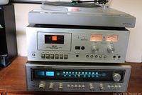 Stacked audio components: NEC turntable on top, AKAI CS-705D tape deck in the middle with lit VU meters and buttons, Nikko 5055 receiver at bottom with blue-lit dial and knobs.