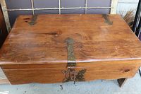Top view of antique wooden chest showing metal latch, hinges, and wood grain surface.