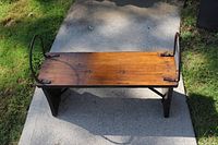 Top view showing wooden seat and black iron armrests curved upward at the ends.