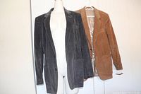 Two vintage men's ribbed corduroy sport jackets on hangers, one blue/grey and one brown, displayed side by side.