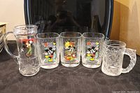 Photo showing five glasses including four McDonalds Mickey Mouse character glasses and one clear glass mug featuring Mickey Mouse golf character
