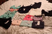 Large lot of Thyme Maternity clothing, mostly bras, tank tops and underwear laid out on a bed showing various colors and sizes, new with tags.