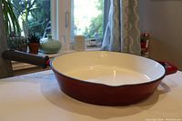 Full side view of the red cast iron skillet showing exterior color and shape.