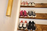 Full overview of six pairs of women's shoes on wooden stairs showing Red Converse, Blue Converse, Fuchsia Nike, Blue Nike, Black/white/peach Nautica, and Black New Balance shoes