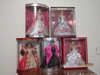 Front facing photo showing all five boxed Barbie dolls arranged on a surface, displaying various holiday-themed dresses and original packaging.