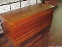 Full view of the closed cedar chest showing medium brown wood with simple grooves on front.