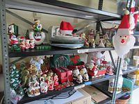 Wide view of Christmas decorative figurines, ceramics, plates, and other assorted items displayed on metal shelving.