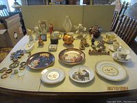 Photo showing full assortment of collectibles including plates, cups, saucers, figurines, and banks arranged on a table.