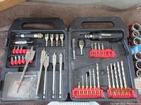Black plastic case with drill bits of various sizes including flat wood spade bits, screwdriver bits, and small socket adapters.