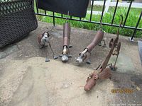 Four rusty metal dog sculptures placed on concrete, showing variety of sizes and movable parts