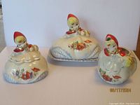 Photo showing all three Little Red Riding Hood dishes together, including creamer, sugar bowl, and butter dish with lids and character figurines.