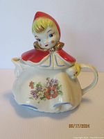 Front view of Little Red Riding Hood teapot showing character face, hood, and front floral decoration.
