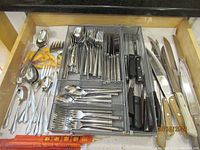 Silverware drawer showing forks, spoons, knives, serving forks, and spoons, chopsticks
