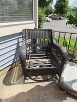 Photo of a brown woven wicker glider swivel club chair without cushions showing frame and area where cushions fit.
