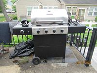 Photo of Char Broil gas grill with four control knobs, wheels, side shelves, and brand logo visible