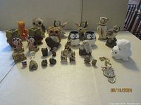 Full view of assembled figurines on table showing variety in materials and styles including wood, ceramic, and glass.