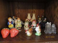 Photo showing multiple ceramic and glass salt and pepper shakers including strawberries, human figures, and farm animals