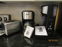 Toaster, two drip coffee makers including a Mr. Coffee with carafe and Amazon Basics model on kitchen counter